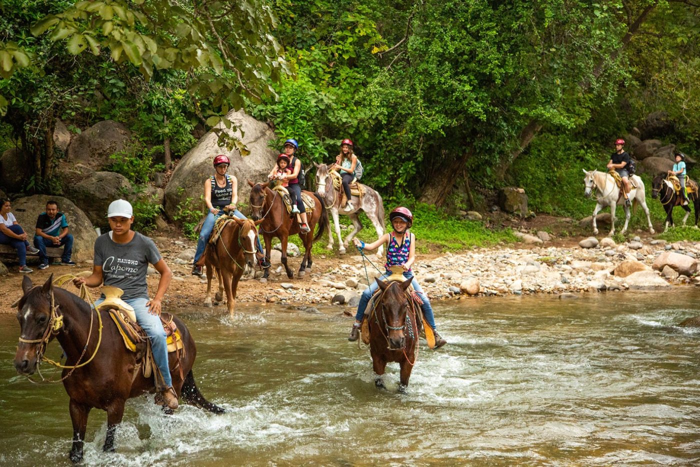 La mejor época para visitar Puerto Vallarta si buscas tours de aventura: guía mes a mes Familia cruzando a caballo un río de la selva cerca de Puerto Vallarta en la temporada verde