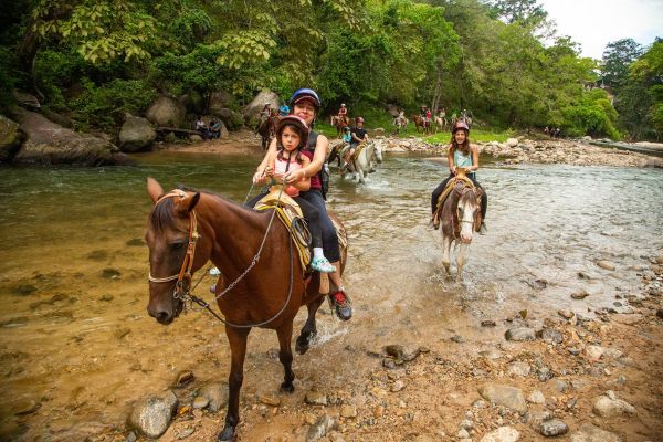 Mujer cruzando el río a caballo en el tour en caballo de la Sierra Madre