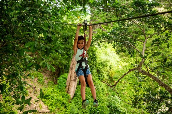 Persona deslizándose en tirolesa entre los árboles en Rancho Capomo, Puerto Vallarta